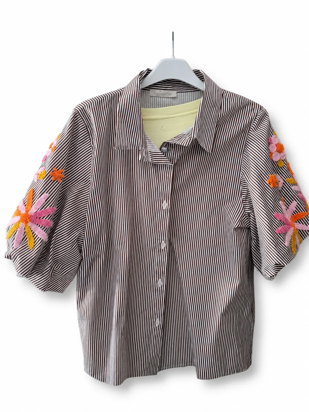 Freigestelltes Produktfoto einer gestreiften Bluse mit bunten Stickereien an den Ärmeln